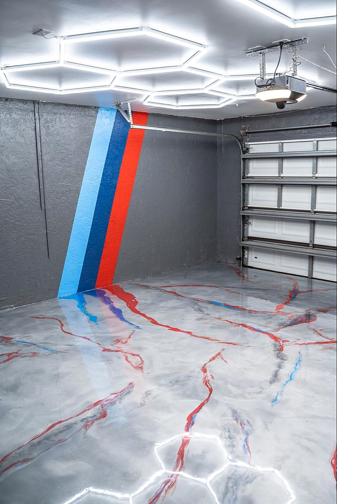Custom garage with white metallic floor, racing stripe, and hex lighting